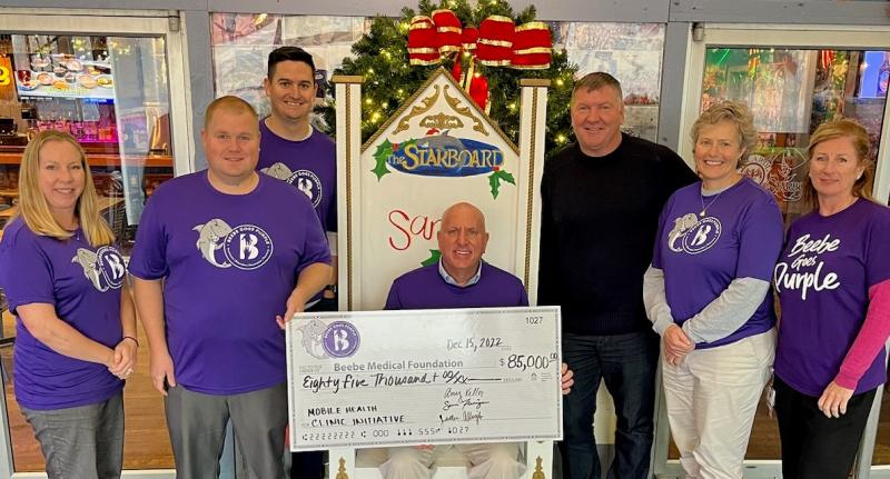 Presenting the Beebe Goes Purple event proceeds are (l-r) Amy Keller, Beebe Medical Foundation event coordinator; Justen Albright, BMF financial analyst; Sean Flanigan, BMF gift officer; Tom Protack, BMF president; Steve Montgomery, The Starboard owner; Kay Young, BMF executive director of development; and Kim Blanch, Beebe Healthcare director of community outreach. SUBMITTED PHOTO